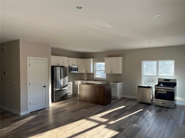 kitchen featuring white cabinets, dark hardwood / wood-style floors, a kitchen island, and appliances with stainless steel finishes