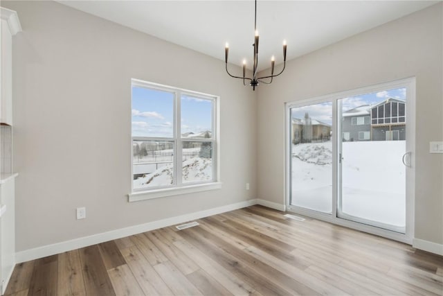 unfurnished dining area with a notable chandelier and light wood-type flooring