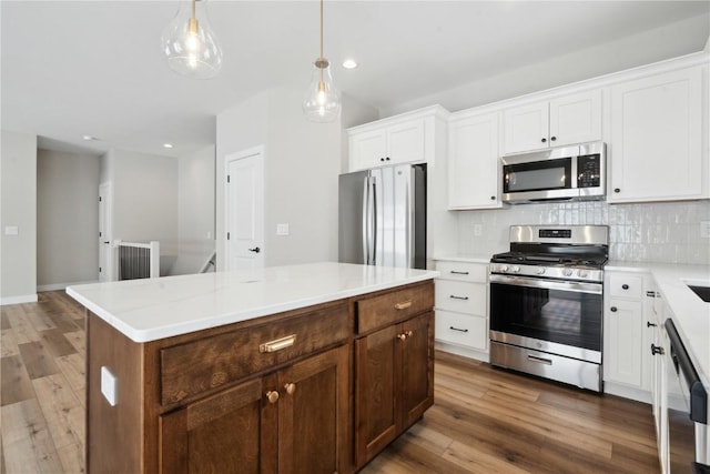 kitchen featuring a center island, white cabinets, pendant lighting, stainless steel appliances, and backsplash