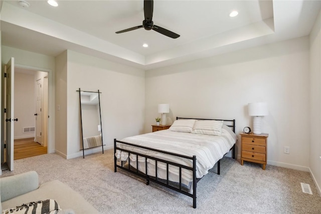 carpeted bedroom featuring a raised ceiling and ceiling fan