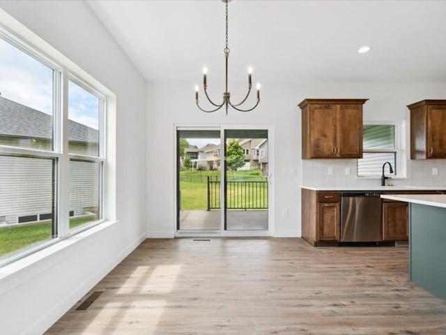 261 Colchester Dr, Iowa City, IA 52245 - kitchen with dishwasher, a chandelier, light countertops, decorative backsplash, and light wood finished floors