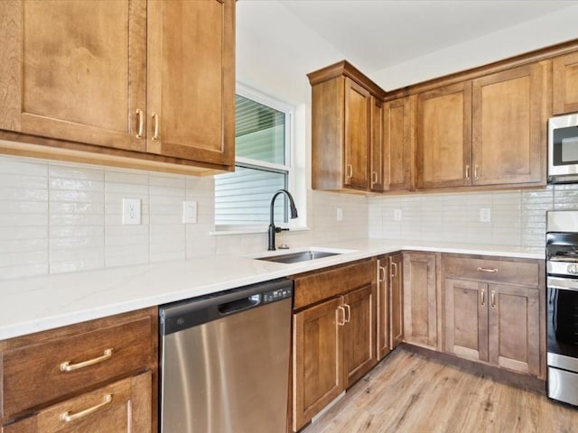 261 Colchester Dr, Iowa City, IA 52245 - kitchen with appliances with stainless steel finishes, a sink, light wood-style flooring, brown cabinetry, and tasteful backsplash