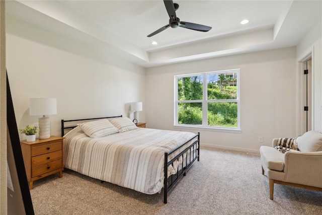 carpeted bedroom with ceiling fan and a tray ceiling