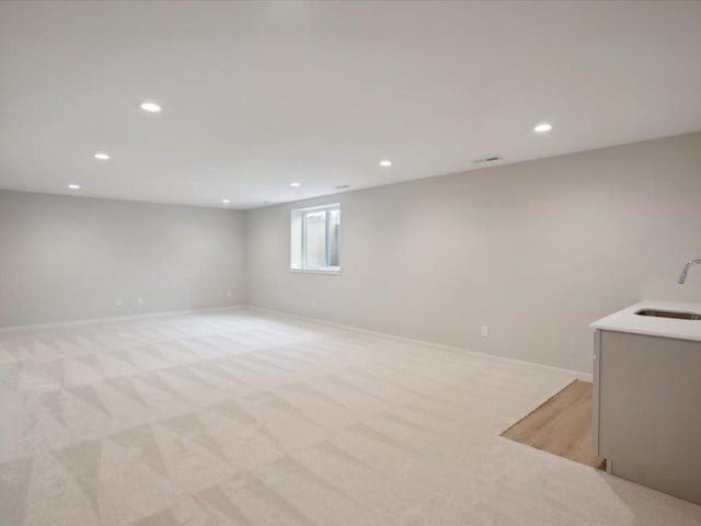 basement featuring light colored carpet and sink