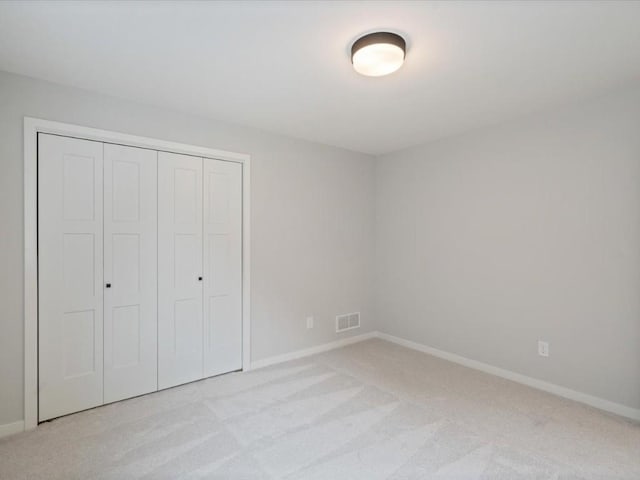 unfurnished bedroom with light colored carpet and a closet