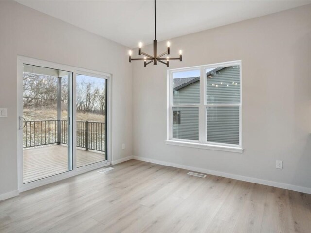 unfurnished dining area featuring light wood-type flooring and an inviting chandelier