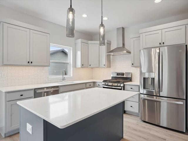 kitchen with sink, a center island, wall chimney range hood, pendant lighting, and appliances with stainless steel finishes