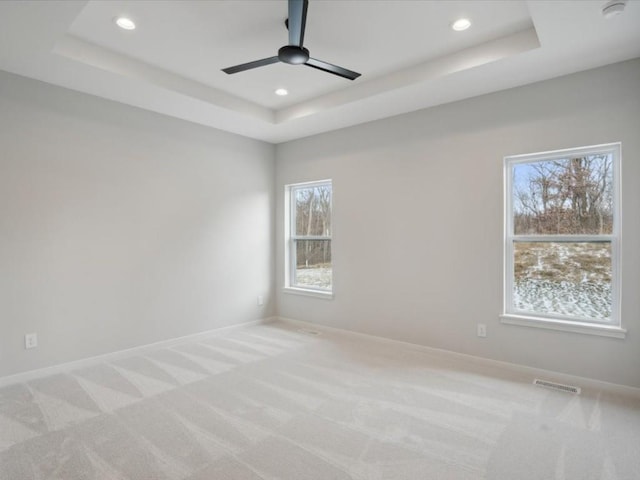 carpeted empty room featuring a tray ceiling and ceiling fan