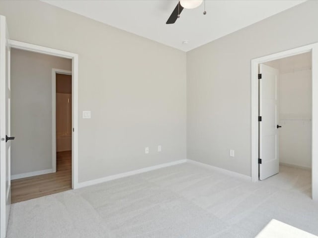 1423 Legend Dr, Tiffin, IA 52340 - unfurnished bedroom with carpet, baseboards, a walk in closet, a ceiling fan, and a closet