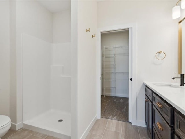 1501 Legend Dr, Tiffin, IA 52340 - bathroom featuring walk in shower, baseboards, a walk in closet, vanity, and toilet