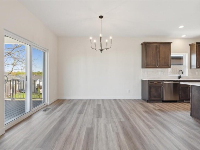 1501 Legend Dr, Tiffin, IA 52340 - kitchen featuring stainless steel dishwasher, a chandelier, light wood-type flooring, light countertops, and decorative backsplash