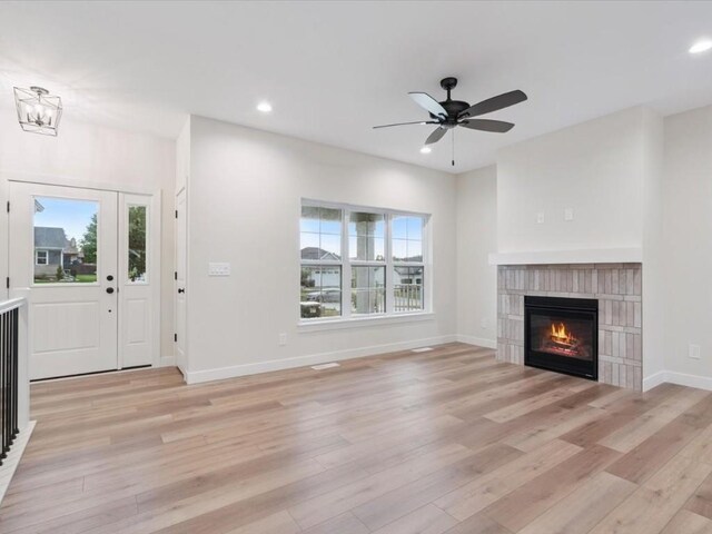314 Sierra Trce, Coralville, IA 52241 - unfurnished living room featuring light wood-type flooring, a glass covered fireplace, a ceiling fan, recessed lighting, and a chandelier