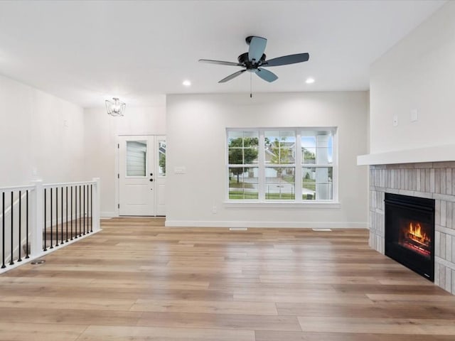 314 Sierra Trce, Coralville, IA 52241 - unfurnished living room with light wood-style flooring, a glass covered fireplace, recessed lighting, a ceiling fan, and a chandelier