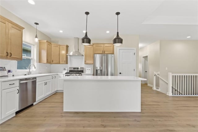 kitchen with decorative light fixtures, light brown cabinetry, stainless steel appliances, and wall chimney range hood