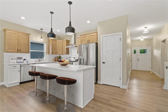 kitchen with a center island, light brown cabinets, light wood-type flooring, decorative light fixtures, and stainless steel appliances