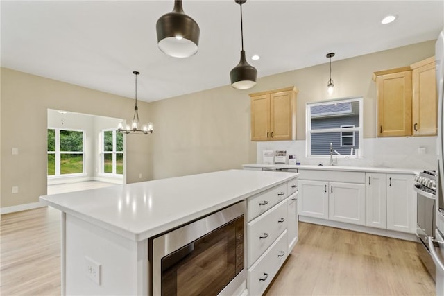 kitchen with tasteful backsplash, stainless steel appliances, light hardwood / wood-style floors, a kitchen island, and hanging light fixtures