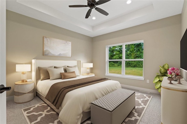 carpeted bedroom featuring a tray ceiling and ceiling fan