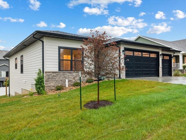 318 Sierra Trce, Coralville, IA 52241 - view of front of house featuring an attached garage, stone siding, driveway, and a front lawn
