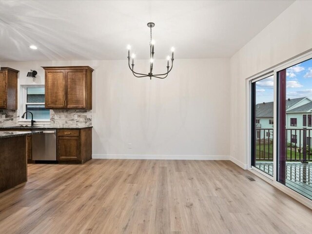318 Sierra Trce, Coralville, IA 52241 - kitchen featuring stainless steel dishwasher, light wood finished floors, a chandelier, backsplash, and decorative light fixtures