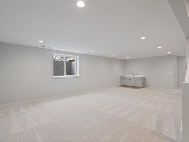 basement featuring light colored carpet and sink