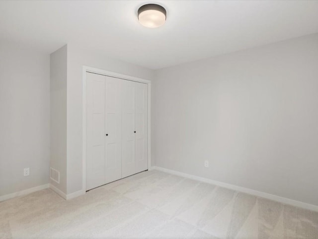 unfurnished bedroom featuring light colored carpet and a closet