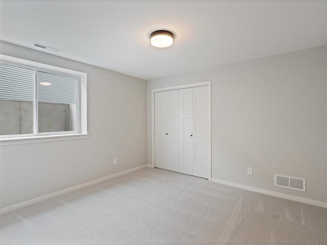 unfurnished bedroom featuring light carpet and a closet