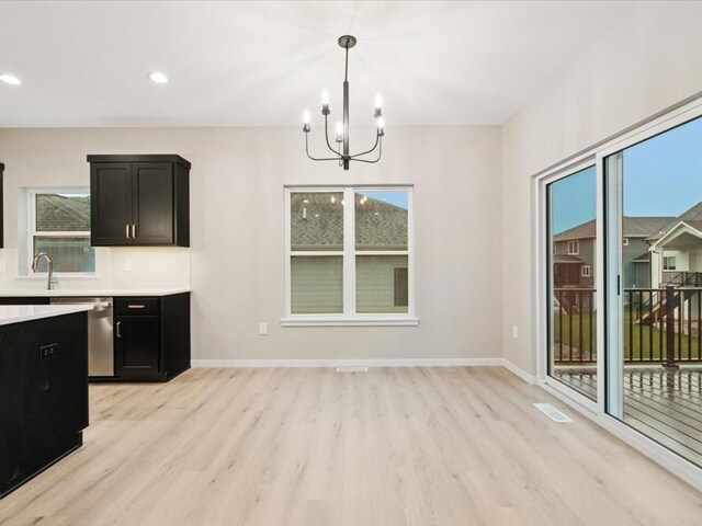 322 Sierra Trce, Coralville, IA 52241 - kitchen featuring stainless steel dishwasher, dark cabinets, light wood finished floors, a chandelier, and light countertops