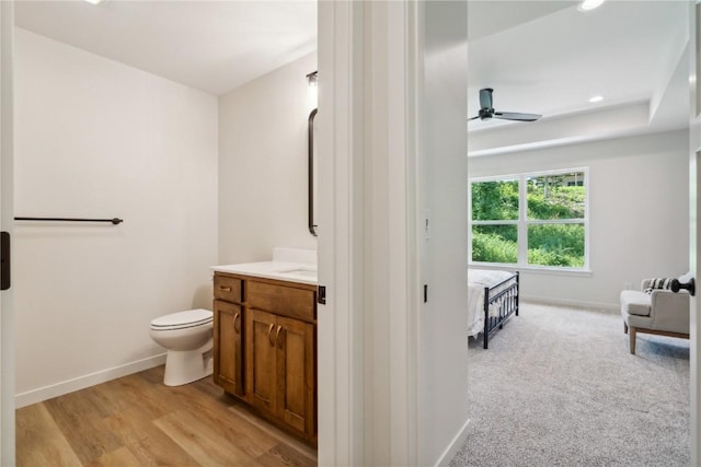 bathroom with hardwood / wood-style floors, vanity, toilet, and ceiling fan