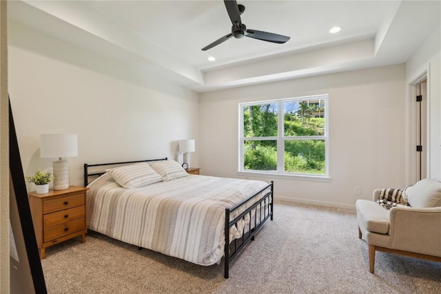 carpeted bedroom featuring a raised ceiling and ceiling fan