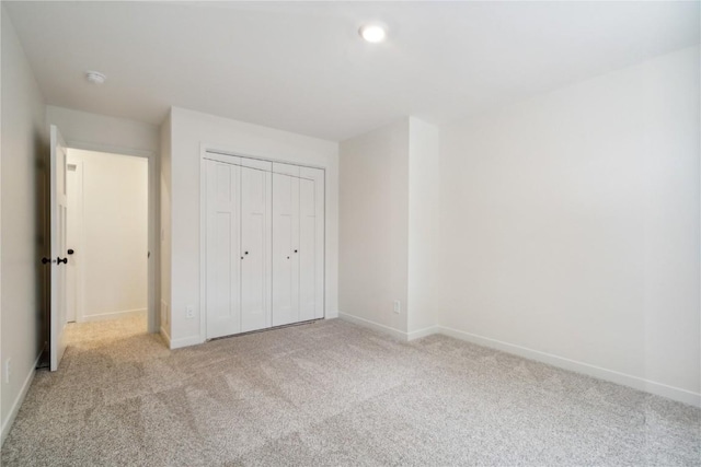 unfurnished bedroom with light carpet and a closet