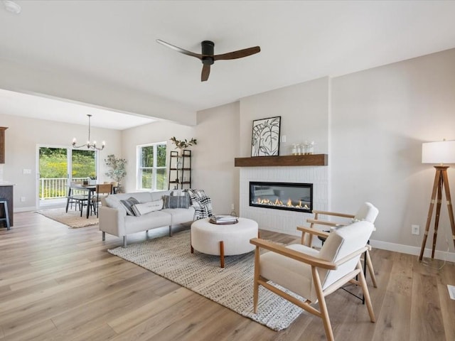 4648 Preston Ln, Iowa City, IA 52246 - living room with a glass covered fireplace, light wood-style flooring, ceiling fan, and a chandelier