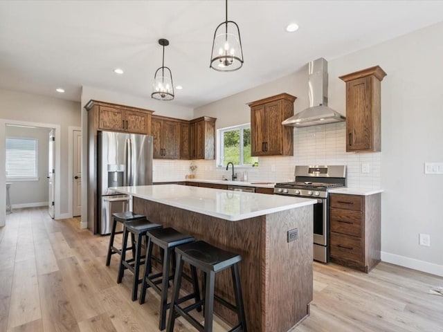 4648 Preston Ln, Iowa City, IA 52246 - kitchen with wall chimney range hood, appliances with stainless steel finishes, a kitchen island, decorative backsplash, and light wood-style floors