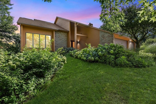 property exterior at dusk with a yard and a garage