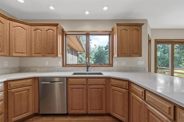 kitchen with a wealth of natural light, sink, stainless steel dishwasher, and light stone counters