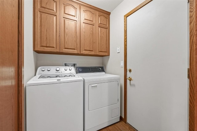 washroom with washer and clothes dryer, light hardwood / wood-style floors, and cabinets