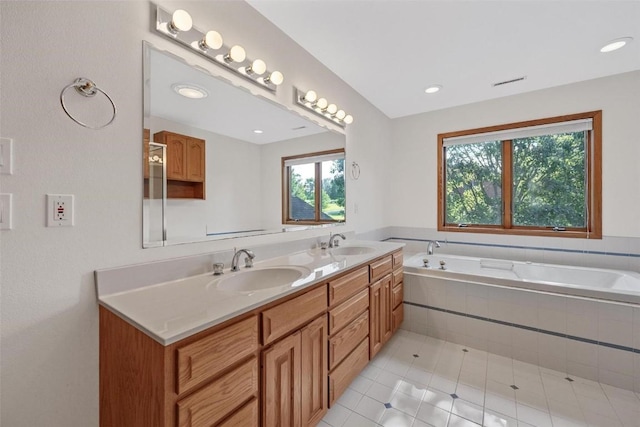 bathroom with tile patterned flooring, vanity, and tiled tub