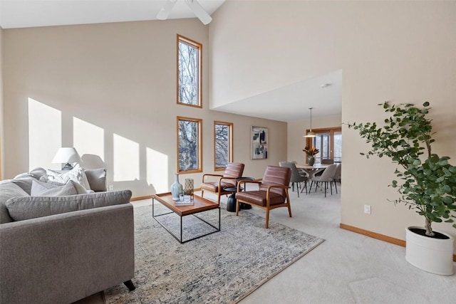 carpeted living room featuring ceiling fan, a towering ceiling, and a healthy amount of sunlight