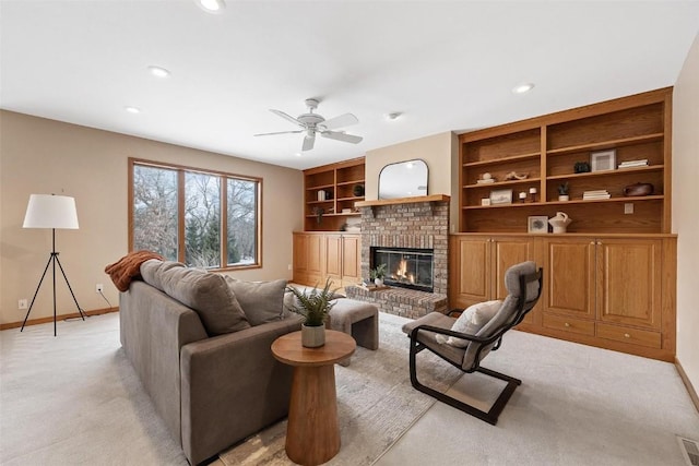 living room featuring light carpet, built in shelves, ceiling fan, and a fireplace