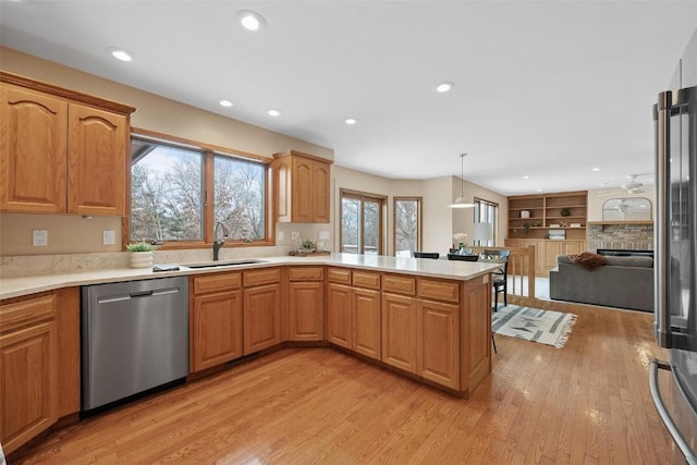 kitchen featuring kitchen peninsula, sink, decorative light fixtures, light hardwood / wood-style flooring, and dishwasher