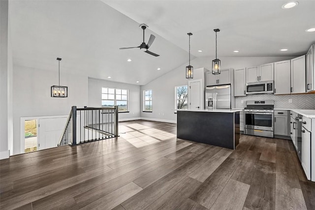 kitchen featuring vaulted ceiling, a kitchen island, stainless steel appliances, and decorative light fixtures