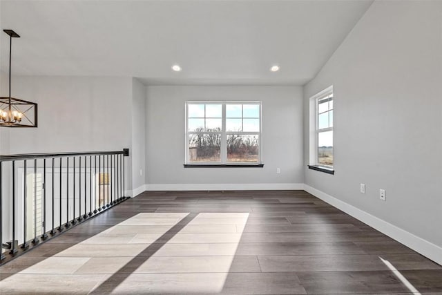 unfurnished room featuring lofted ceiling, dark hardwood / wood-style flooring, and a notable chandelier