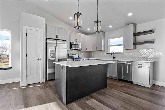 kitchen featuring a center island, dark hardwood / wood-style flooring, pendant lighting, vaulted ceiling, and appliances with stainless steel finishes