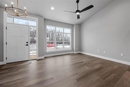 foyer entrance with vaulted ceiling, ceiling fan with notable chandelier, and dark hardwood / wood-style floors