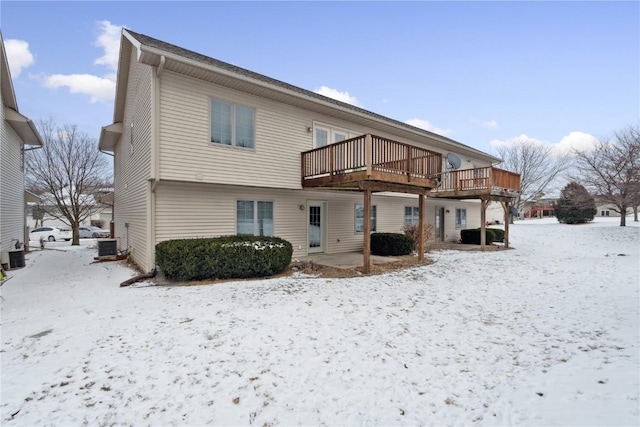 snow covered back of property featuring central air condition unit and a deck