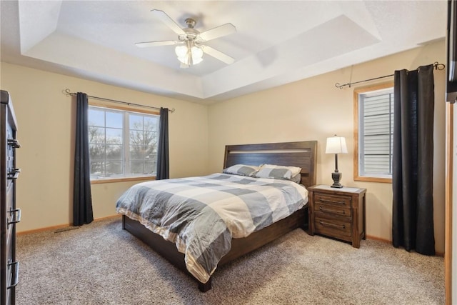 carpeted bedroom with a tray ceiling and ceiling fan