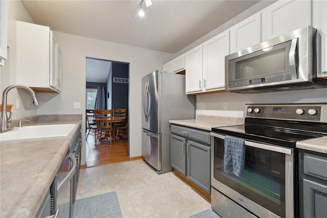 kitchen with gray cabinets, white cabinetry, sink, and appliances with stainless steel finishes