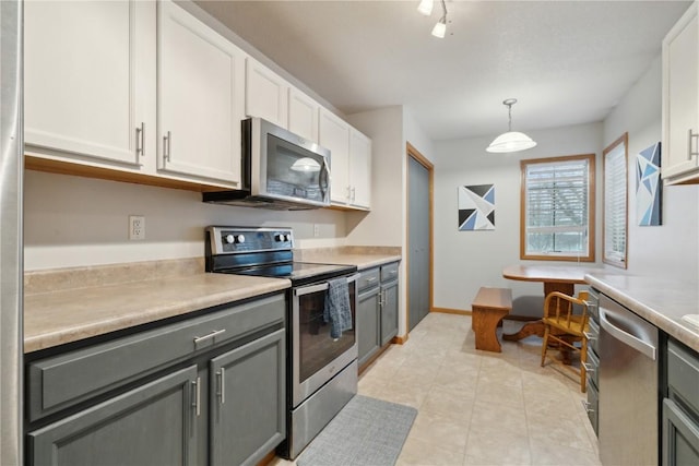 kitchen featuring rail lighting, stainless steel appliances, pendant lighting, gray cabinets, and white cabinets