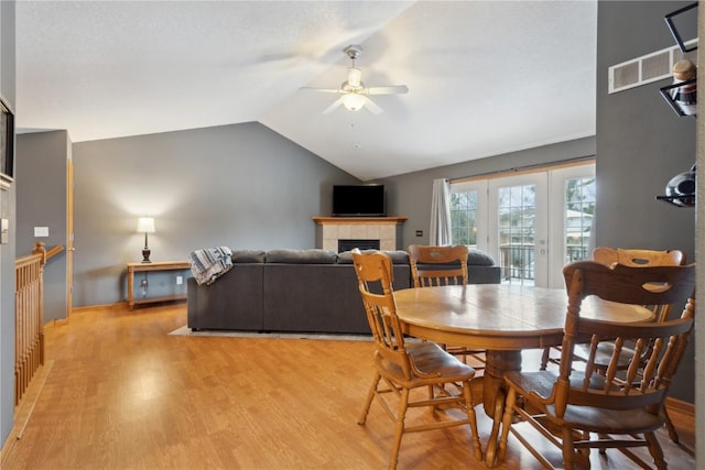 dining space with a fireplace, light hardwood / wood-style floors, ceiling fan, and lofted ceiling