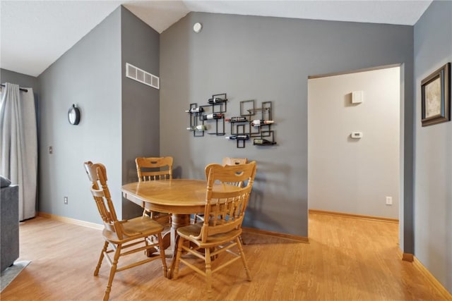 dining space with light wood-type flooring and lofted ceiling