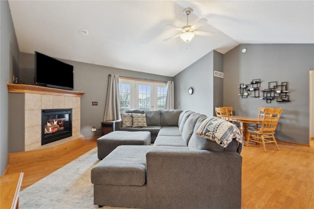 living room featuring a tile fireplace, ceiling fan, lofted ceiling, and hardwood / wood-style flooring